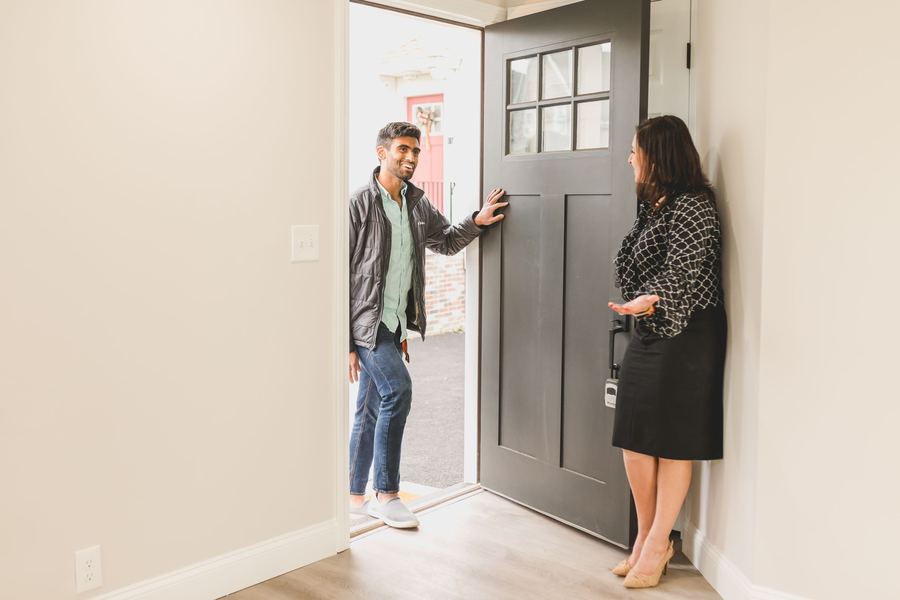 An agent welcoming a visitor into a home for sale