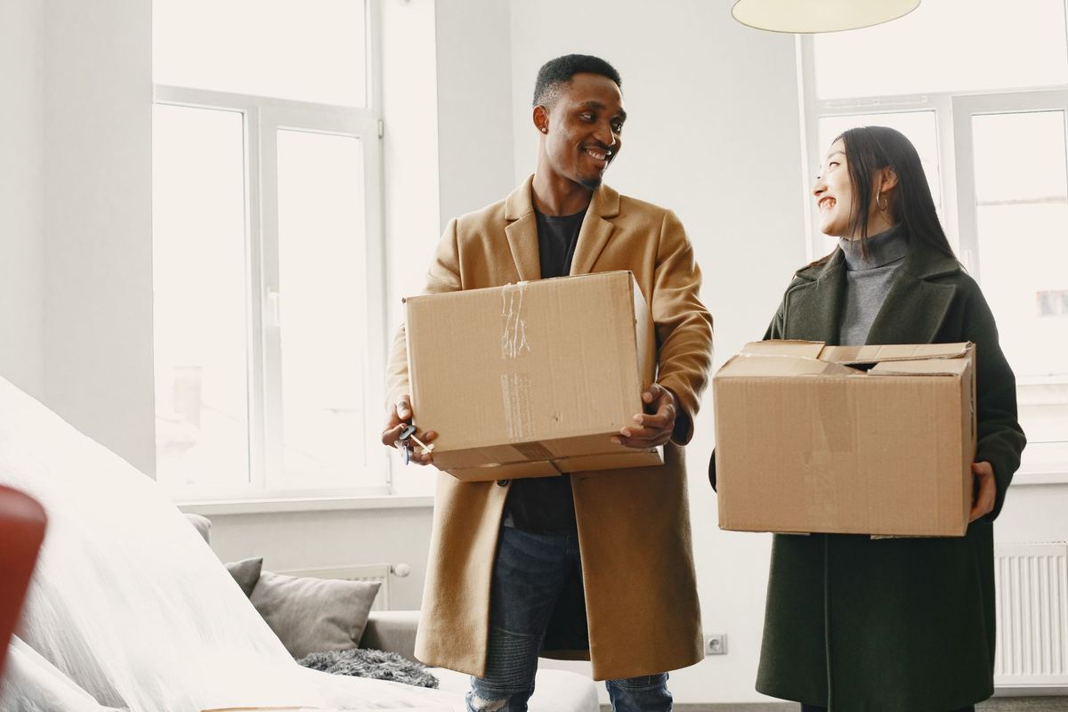 A happy couple carrying boxes into their new home